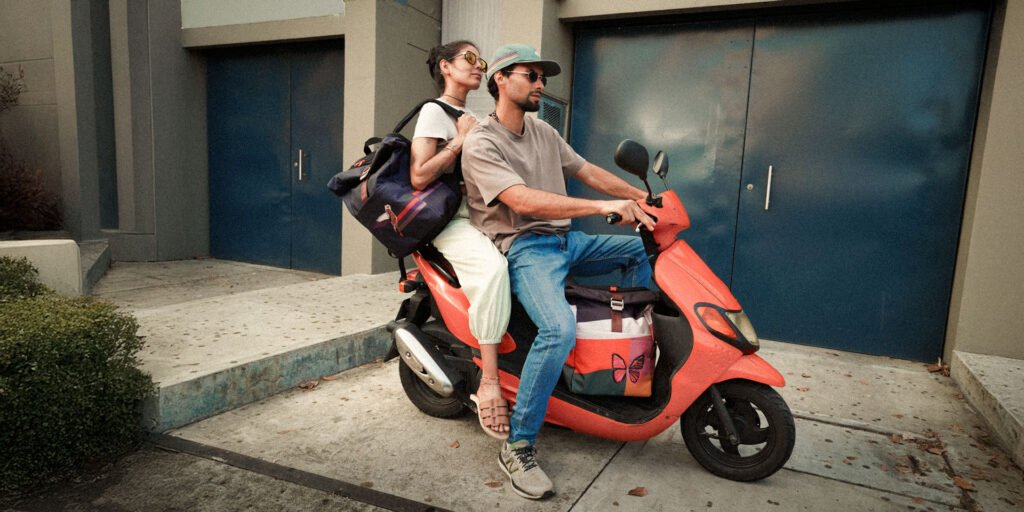 mont backpacks Two people riding a coral scooter through a city street, one wearing a Mônt backpack